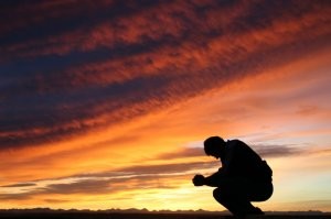 man praying at sunset